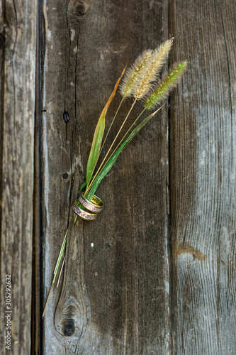 Gold wedding rings on the wood with flower grass - image