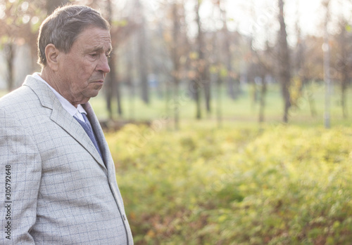 Senior man walking and relaxing in park. Walking away, relaxing, side view