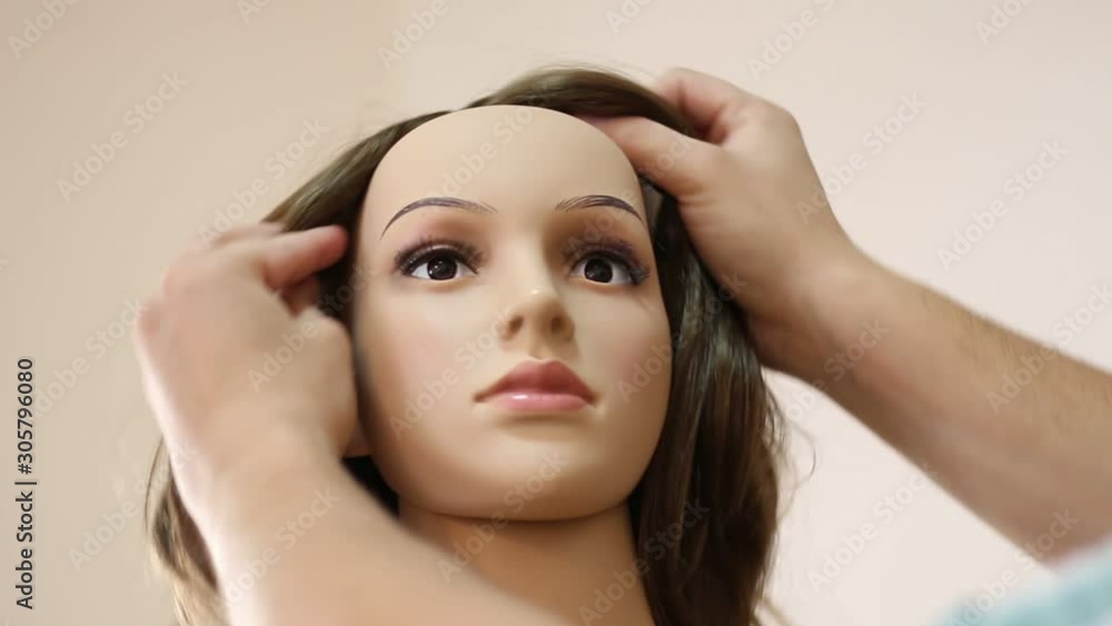Man puts a wig on a female mannequin Man puts a wig on a female mannequin