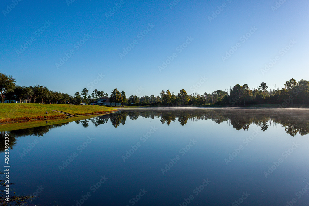 Early morning lake view with reflection of trees in the water