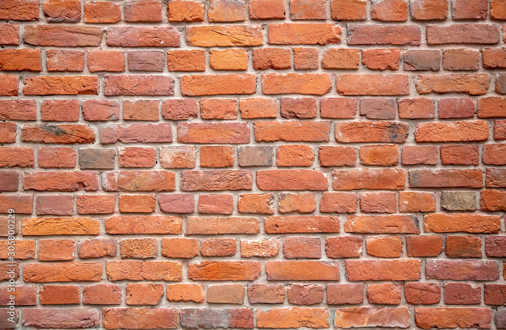 old red, orange ragged brick wall with gray cement, stains of white paint. rough surface texture old red, orange ragged brick wall with gray cement, stains of white paint. rough surface texture