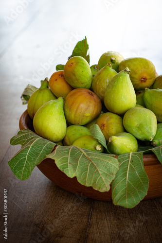 Wooden bowl full of fresh green figs on dark wooden table