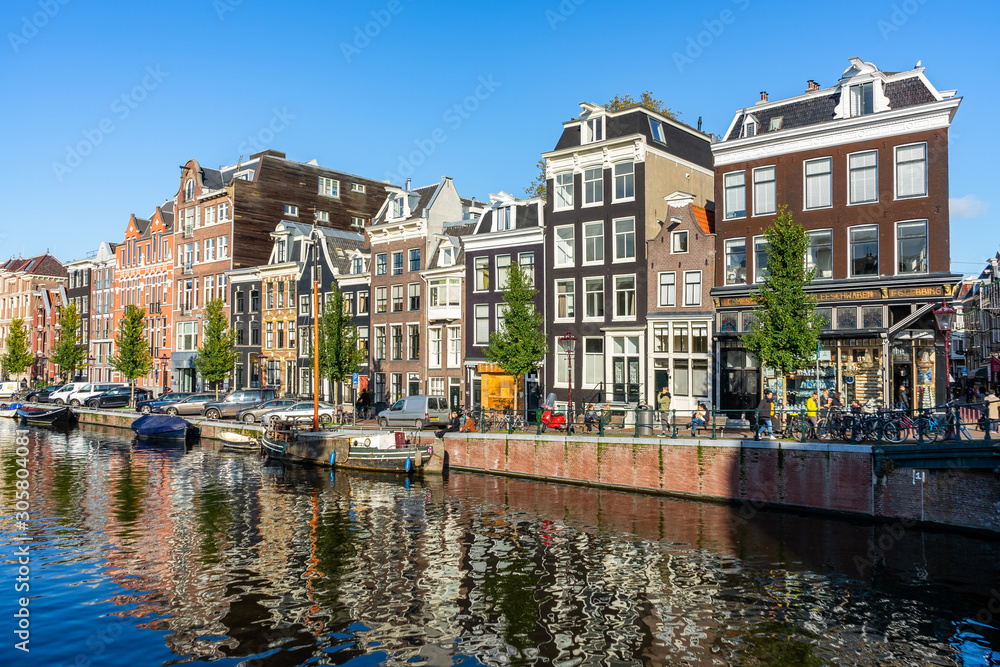 House reflection in the canals of Amsterdam, autumn colors and blue sky