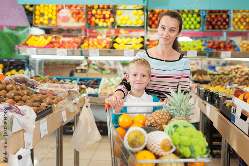 mother with little boy buying fruits and vegetables at store