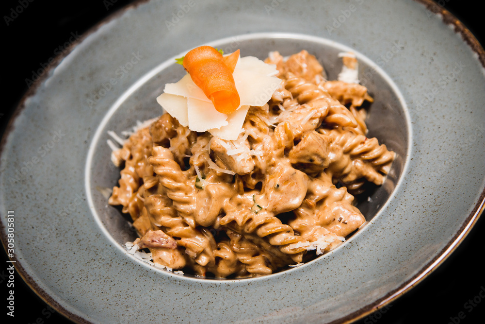 Homemade pasta with chicken, cheese and piece of carrot in a rustic plate Homemade pasta with chicken, cheese and piece of carrot in a rustic plate