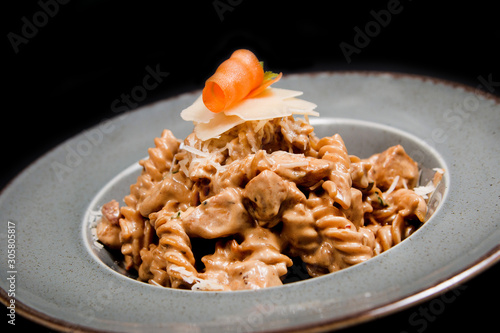 Homemade pasta with chicken, cheese and piece of carrot in a rustic plate