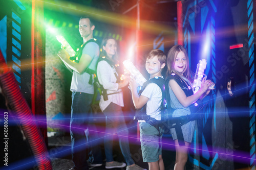 Kids standing back to back on beams with laser pistols