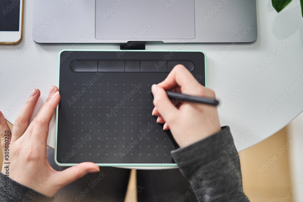 A young girl draws on a graphics tablet. Freelancer works in a cafe A young girl draws on a graphics tablet. Freelancer works in a cafe