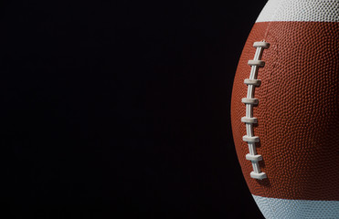 American football ball close up on black background.