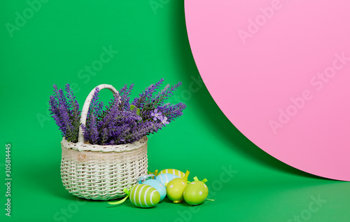 Fototapeta Naklejka Na Ścianę i Meble -  Eater basket with flowers and eggs on colored green background. Copy space for text on right