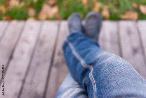 Sit on the bench. Look down at your feet. Sitting in jeans in the park. © Михаил Шаповалов