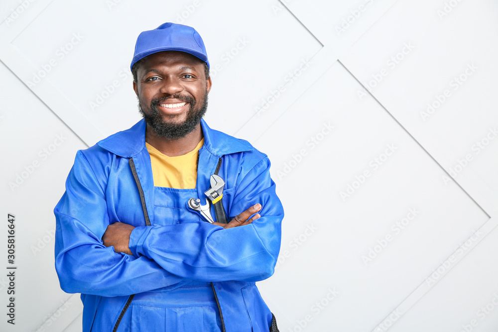 African-American car mechanic near light wall African-American car mechanic near light wall