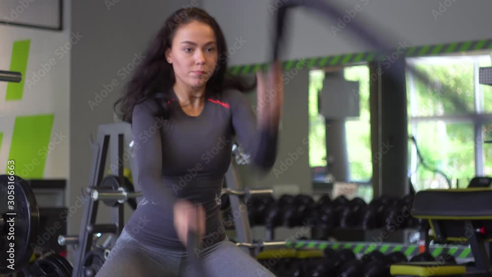 Young girl exercising hard with battle rope during cross training session Young girl exercising hard with battle rope during cross training session