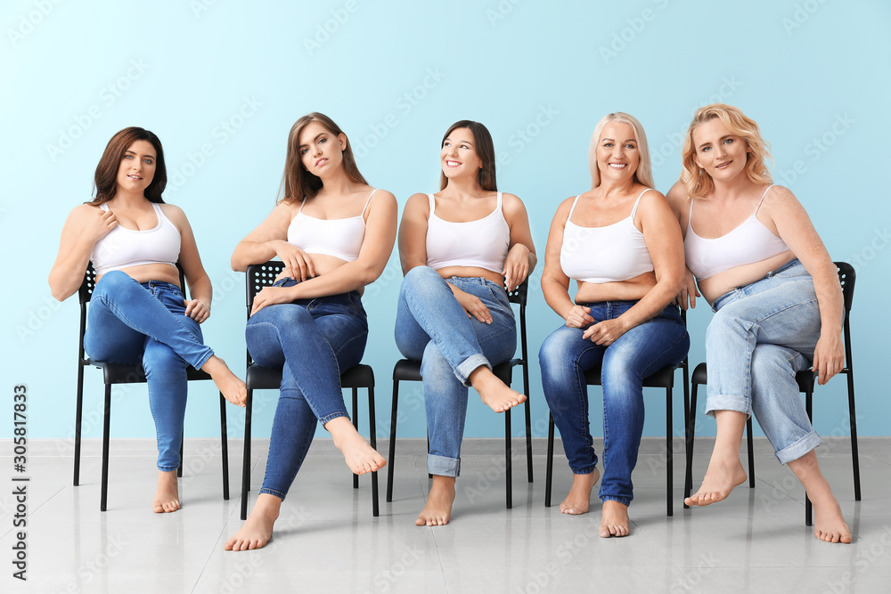 Fototapeta premium Group of body positive women sitting on chairs near color wall