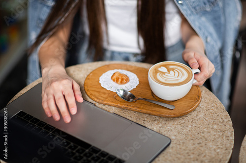 Hands of business woman wich sitting in a cafe. There s a laptop in front of her and cup of coffee. Business concept and co-working space. Horizontal