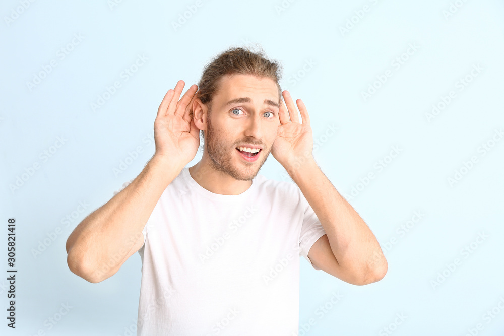 Young man with hearing problem on light background Young man with hearing problem on light background