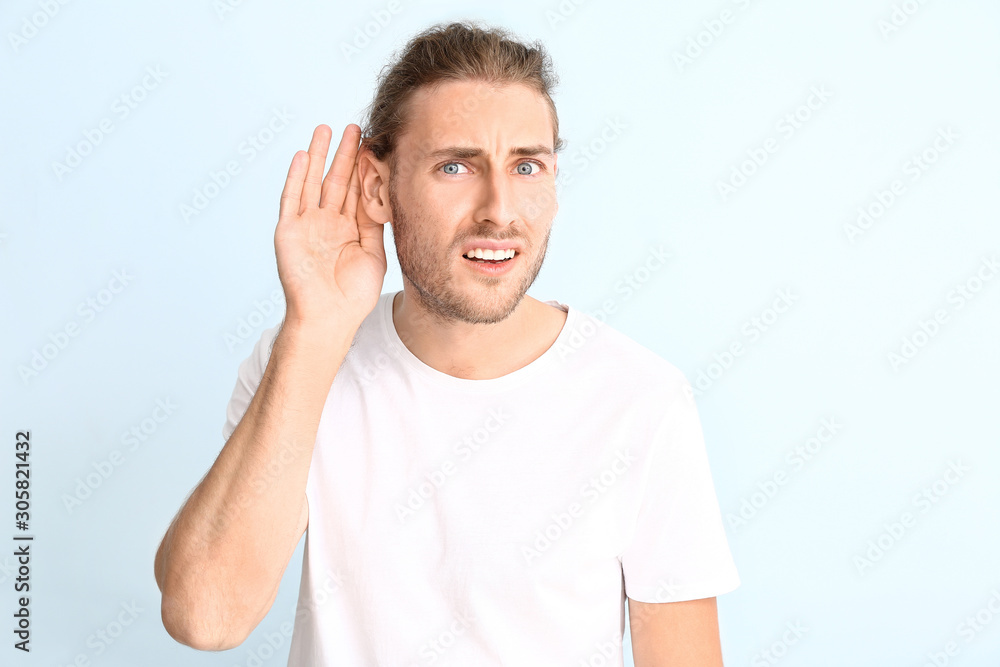 Young man with hearing problem on light background Young man with hearing problem on light background