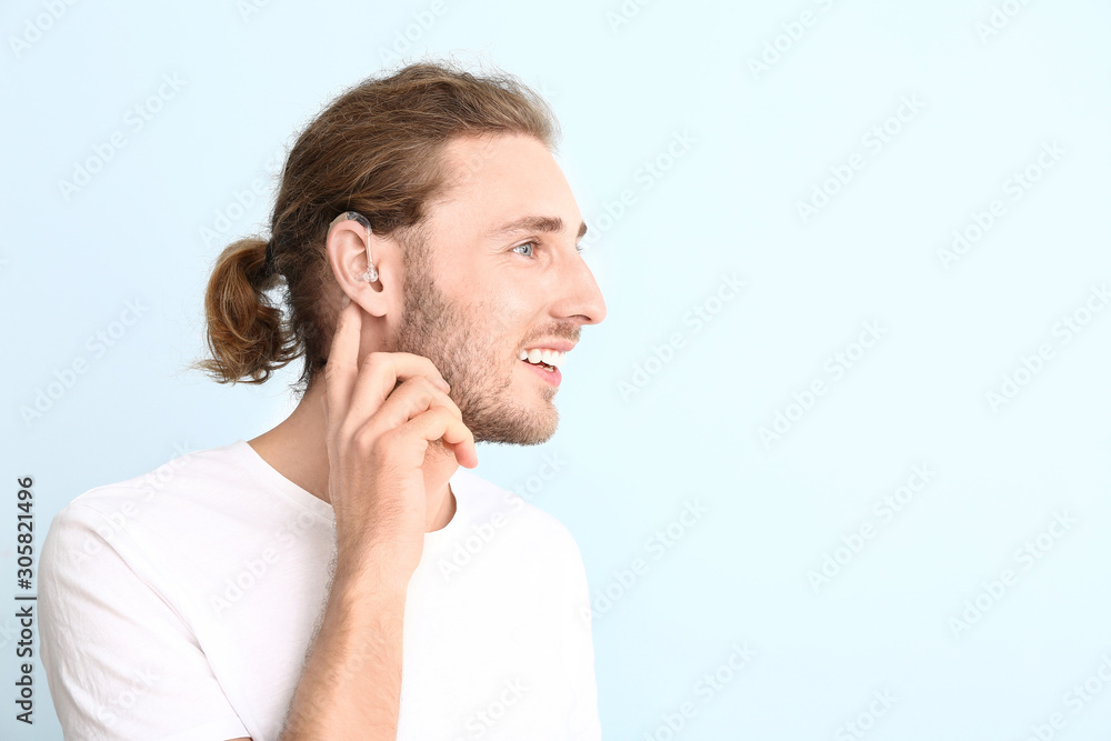 Young man with hearing aid on color background Young man with hearing aid on color background