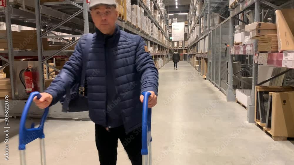 man in a jacket carries a large shopping trolley in a self-service furniture store, a shopping concept man in a jacket carries a large shopping trolley in a self-service furniture store, a shopping concept