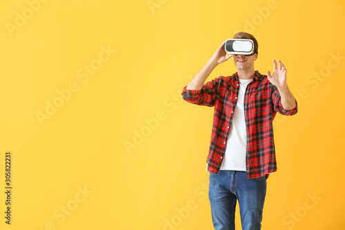 Young man with virtual reality glasses on color background © Pixel-Shot