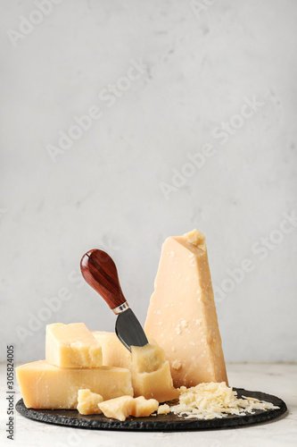Slate plate with tasty Parmesan cheese on light background