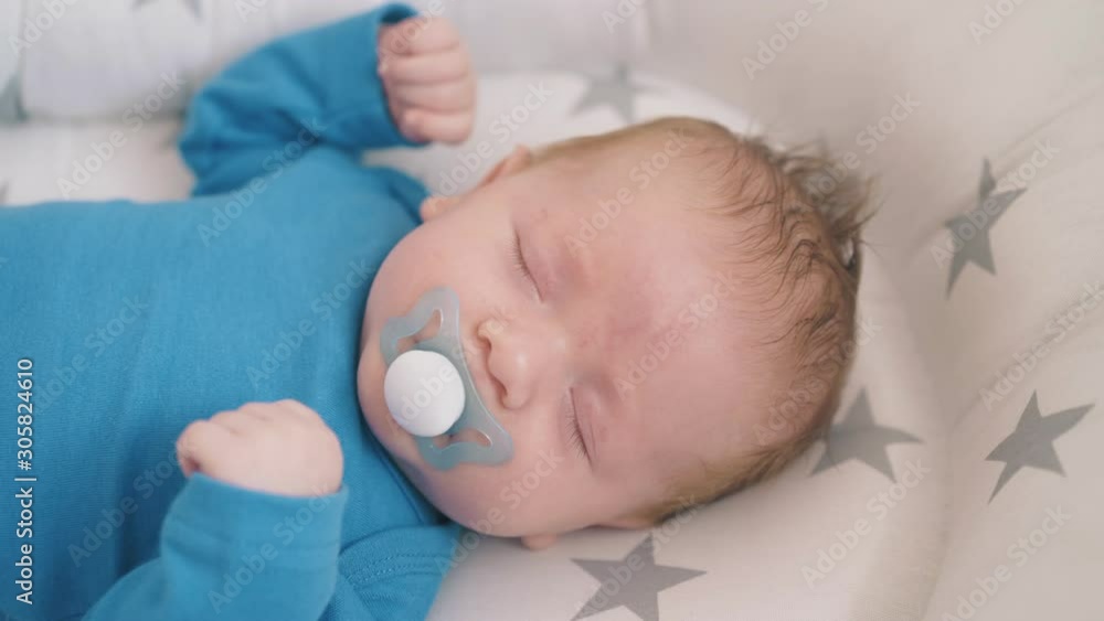 lovely small newborn child with pacifier awakes from nightmare in soft cocoon in rocking cot at home close view lovely small newborn child with pacifier awakes from nightmare in soft cocoon in rocking cot at home close view