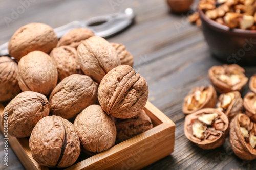 Box with tasty walnuts on wooden background