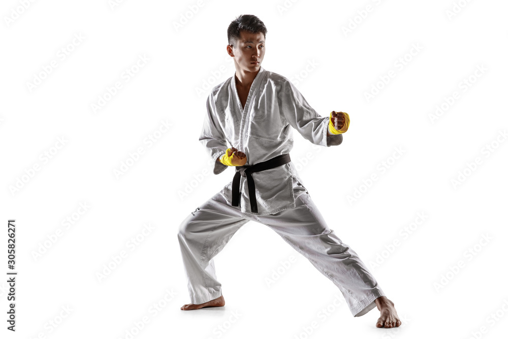 Confident korean man in kimono practicing hand-to-hand combat, martial arts. Young male fighter with black belt training isolated on white studio background. Concept of healthy lifestyle, sport. Confident korean man in kimono practicing hand-to-hand combat, martial arts. Young male fighter with black belt training isolated on white studio background. Concept of healthy lifestyle, sport.