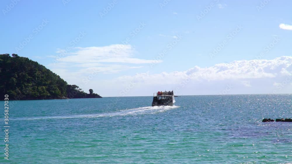 Boat sailing away after bringing tourists to the beach of Abel Tasman park Boat sailing away after bringing tourists to the beach of Abel Tasman park