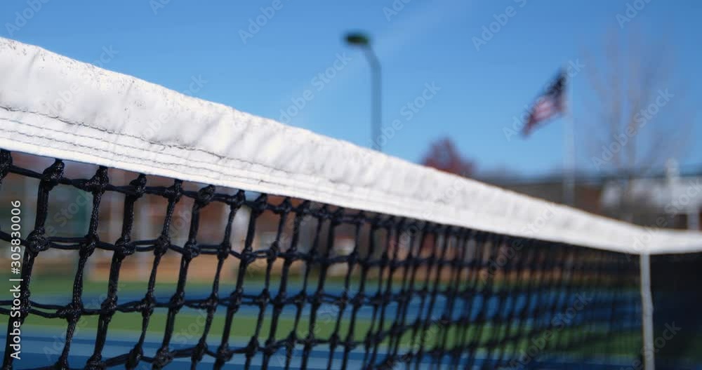 A tennis net that rack focuses to an American flab in the background, and then back again. Shot 60 fps, 4K. A tennis net that rack focuses to an American flab in the background, and then back again. Shot 60 fps, 4K.