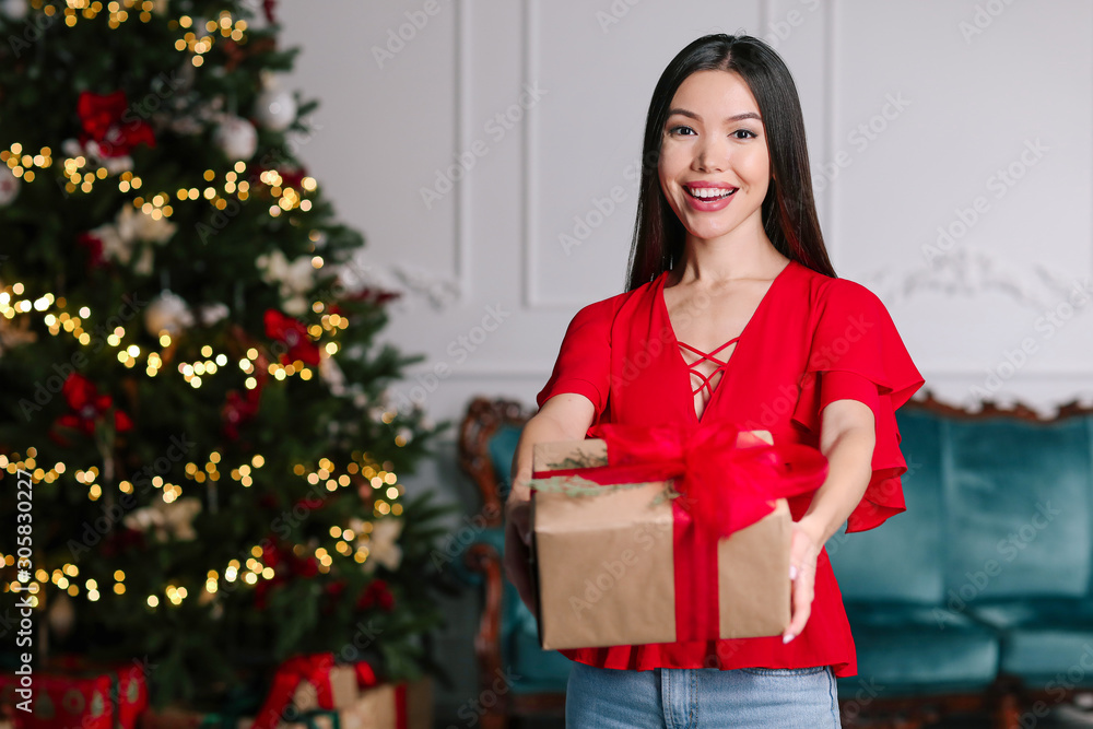 Beautiful young Asian woman with Christmas gift at home Beautiful young Asian woman with Christmas gift at home