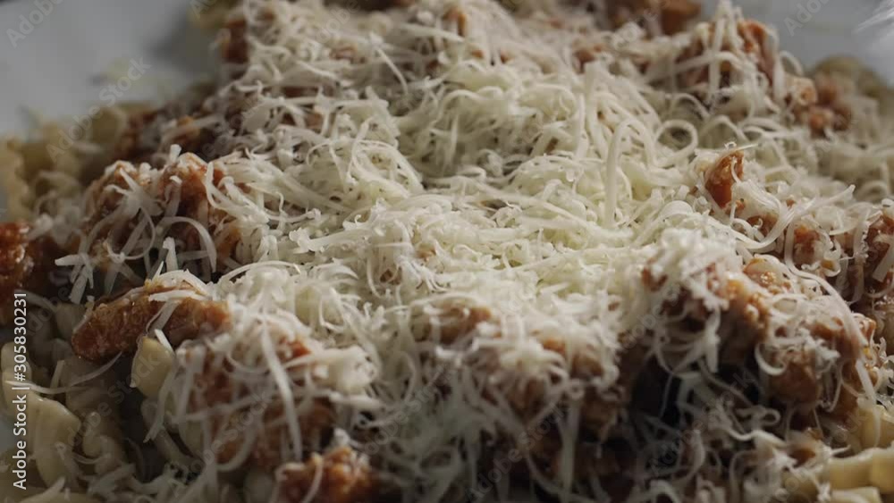 Parmesan cheese falling on Fusilli pasta with meat sauce, slow motion Parmesan cheese falling on Fusilli pasta with meat sauce, slow motion