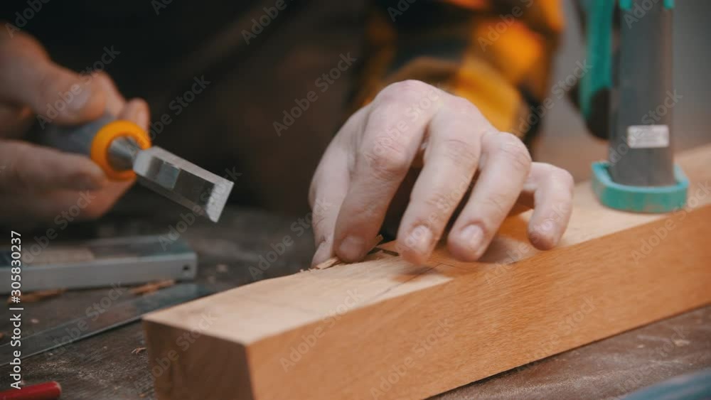 Carpentry - a woodworker cutting out the recess on the wooden block with a chisel Carpentry - a woodworker cutting out the recess on the wooden block with a chisel