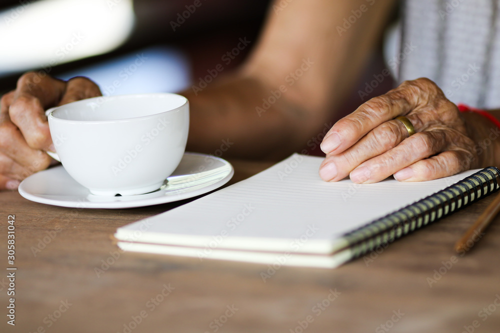 Old asian woman with white coffee cup on wooden table Old asian woman with white coffee cup on wooden table