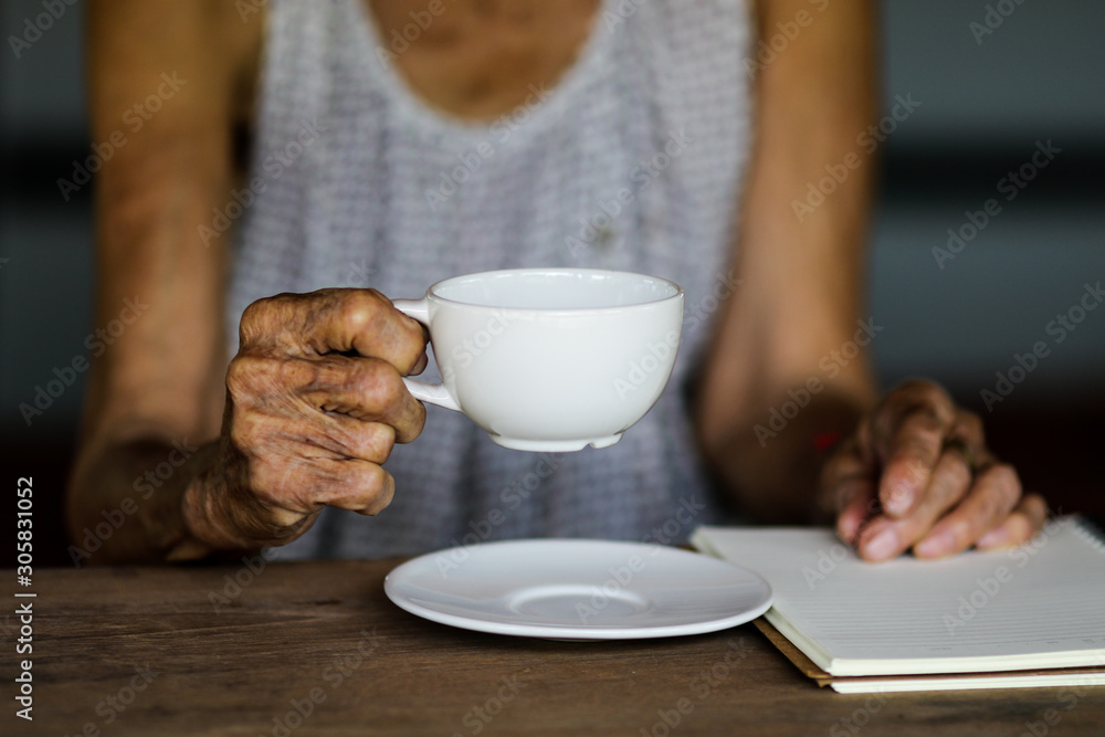 Old asian woman with white coffee cup on wooden table Old asian woman with white coffee cup on wooden table