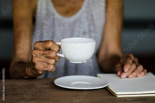 Old asian woman with white coffee cup on wooden table