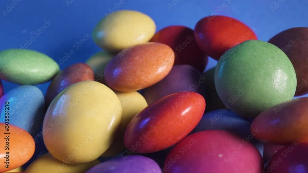 Multicolored candy falling into bowl, close up macro