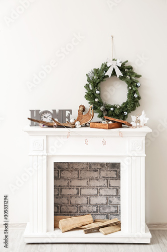 Beautiful Christmas wreath hanging on wall near fireplace with decor