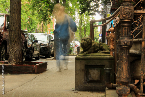 A figure of a woman walks on a sidewalk in front of a building in New York with handrails and some animals figures