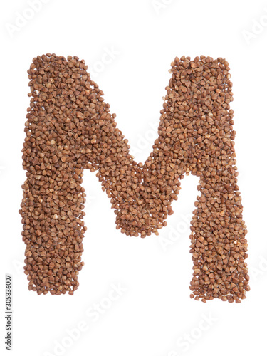 Letter M of the English alphabet from brown dry buckwheat on a white isolated background. Food pattern made from groats. Bright alphabet for shops. Buckwheat for porridge