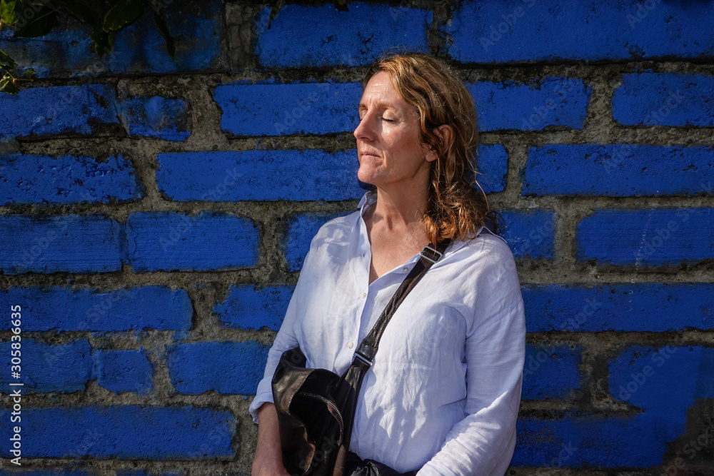 Istanbul, Turkey A tourist woman standing in the sun in the Balat neoghborhood along a blue wall. Istanbul, Turkey A tourist woman standing in the sun in the Balat neoghborhood along a blue wall.