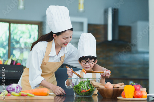 Happy family. Asian mother and son in the kitchen. The mother and son help make a vegetable salad by teaching children to make healthy salad dishes for dinner.