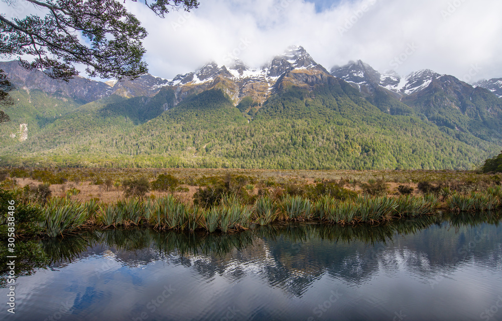 Spectacular landscape of reflections of the Earl mountain ranges on Mirror lake the popular tourist destination in Fiordland national park, New Zealand.