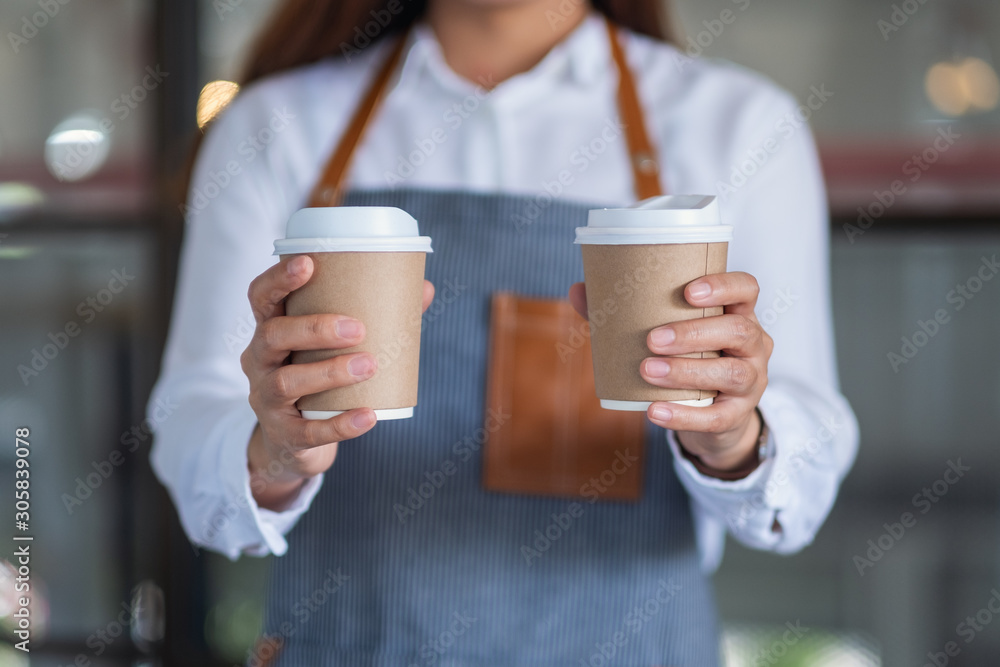 A waitress holding and serving two paper cups of hot coffee in cafe A waitress holding and serving two paper cups of hot coffee in cafe