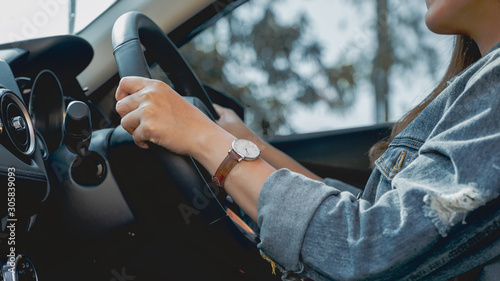 Closeup image of a woman holding steering wheel while driving a car