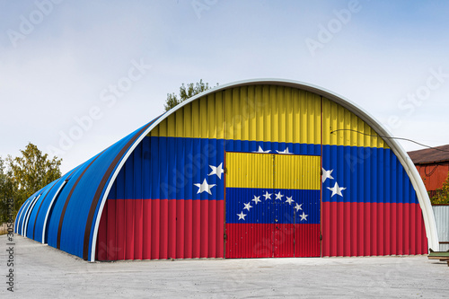 Close-up of the national flag of Venezuela. painted on the metal wall of a large warehouse the closed territory against blue sky. The concept of storage of goods, entry to a closed area, logistics