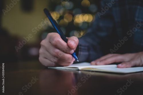 Woman hand writing down in small white memo notebook for take a note not to forget or to do list plan.