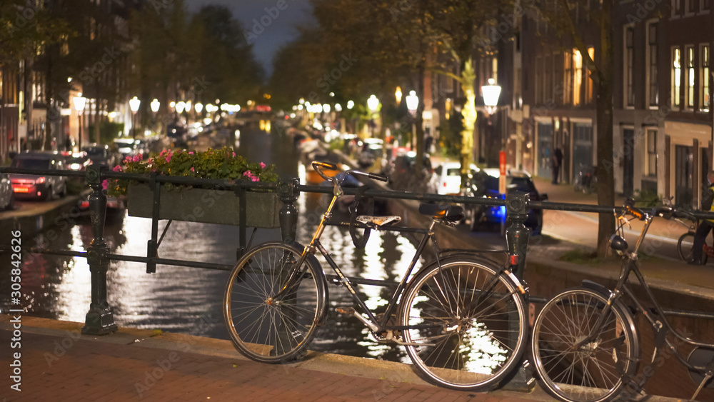 night shot of a bicycle on a bridge over a canal at amsterdam in the netherlands