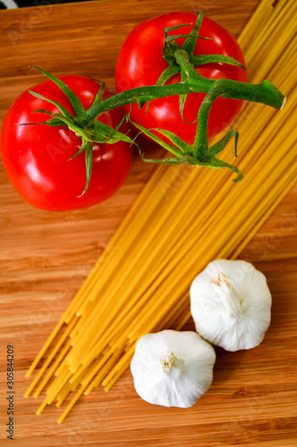 Ingredients used to make an Italian meal. Tomatos, bell peppers, garlic and spagetti 