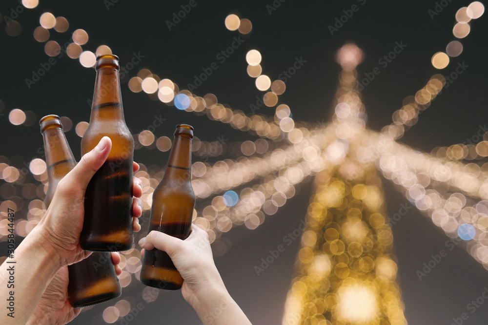 Hands holding beer bottles and happy enjoying harvest time together to  clinking glasses at outdoor party on beautiful bokeh night light  background.Celebration drinking beer in pub orbar. Photos
